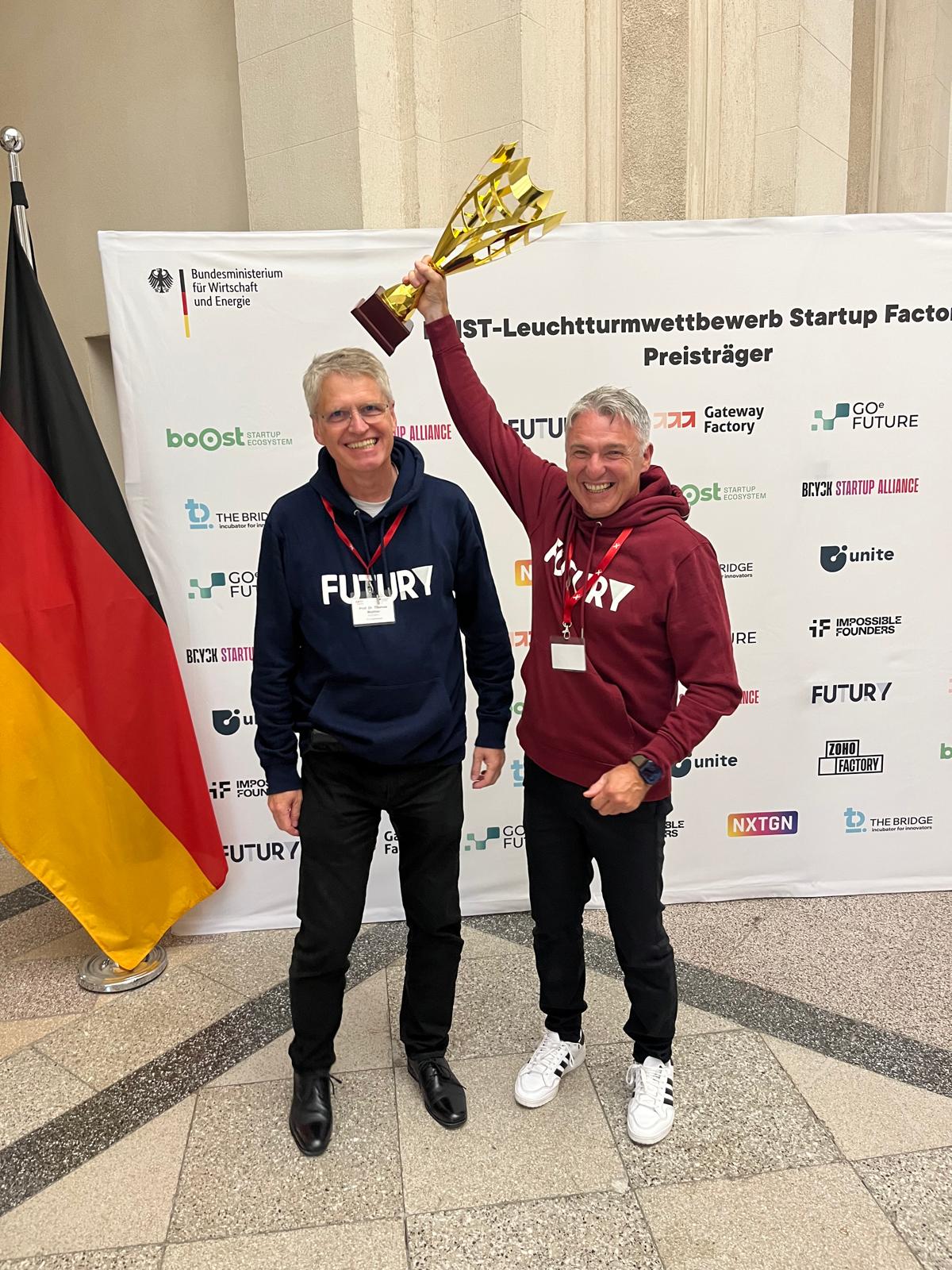 Thomas Walther und Harald Holzer mit einem Pokal bei der Verkündung des Leuchtturmwettbewerbs im Juli 2025 in Berlin
