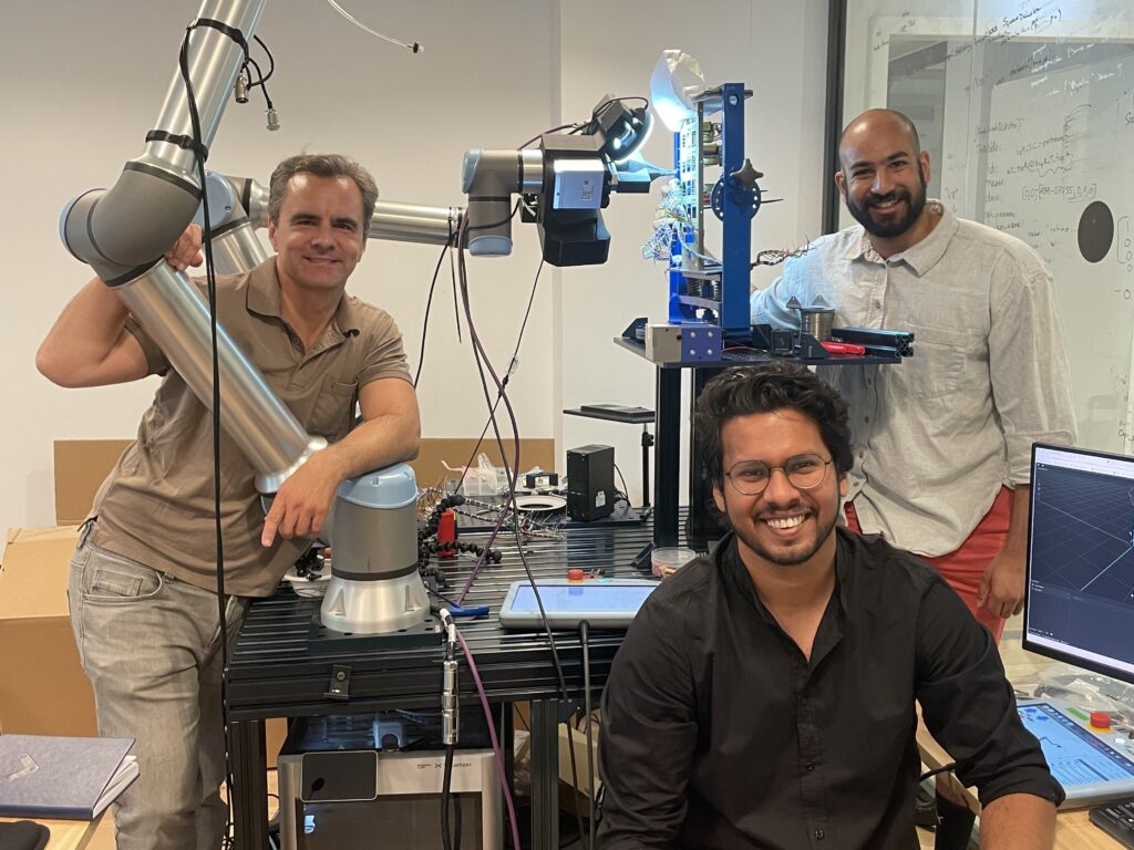 Die Gründer von Telekinesis, Suman Pal (vorne) und Arjun Vir Datta (rechts) mit ihrem Mentor und Berater Jan Peters (links) vor einem KI-Roboter für Siemens/Deutsche Bahn. (Foto: Anja Störiko)